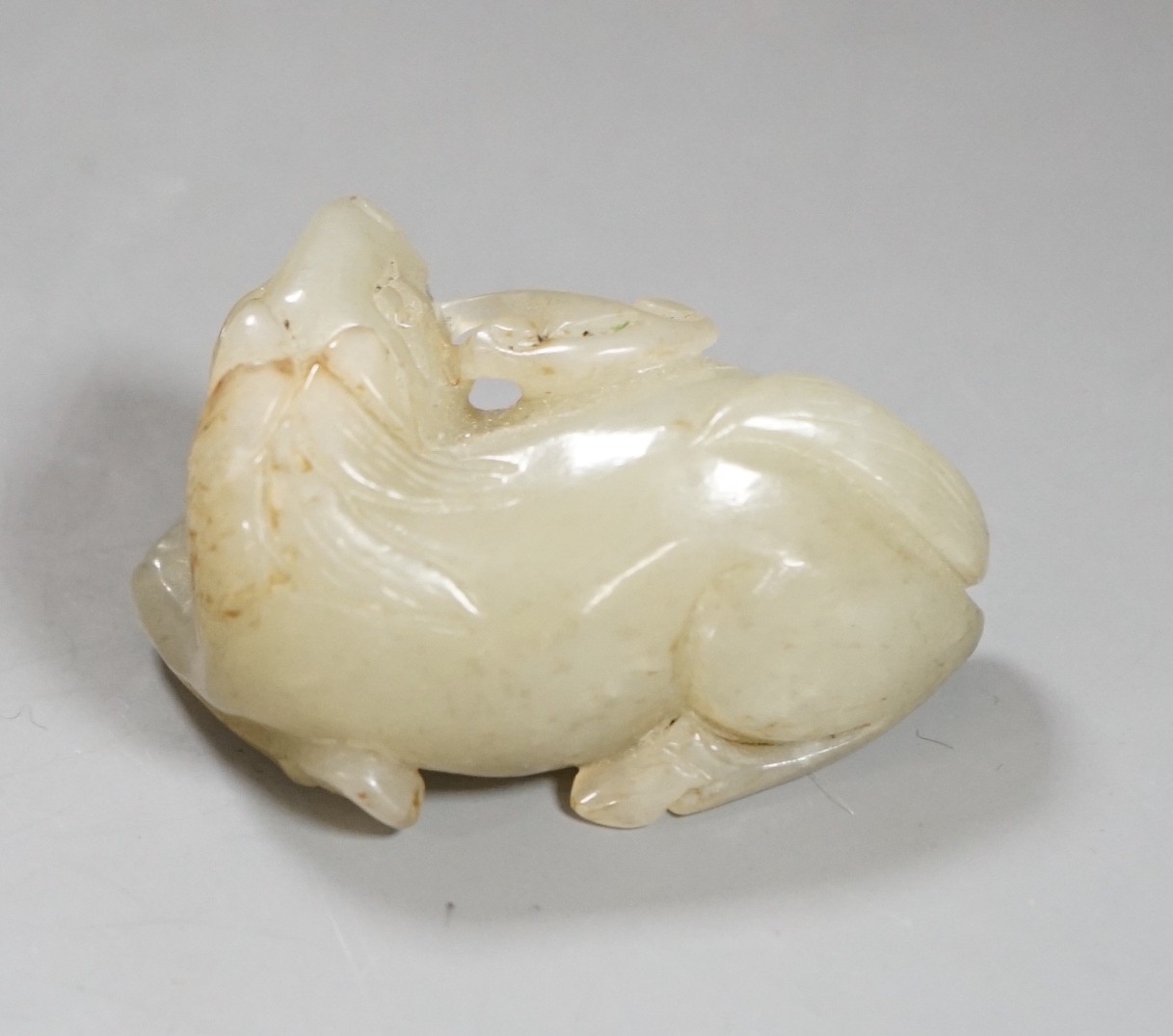 A 19th century Chinese pale celadon jade figure of a seated horse, 6cm wide